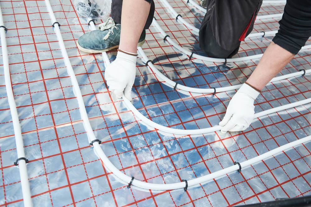 Floor Heating System. Pipe Fitter Mounting Underfloor Heating. Heating System With Hot Water Circulation In Pipes